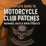 Biker wearing a leather vest with three-piece motorcycle club patch featuring skull and wings at sunset — complete guide to motorcycle club patches, meanings, rules, and biker etiquette.